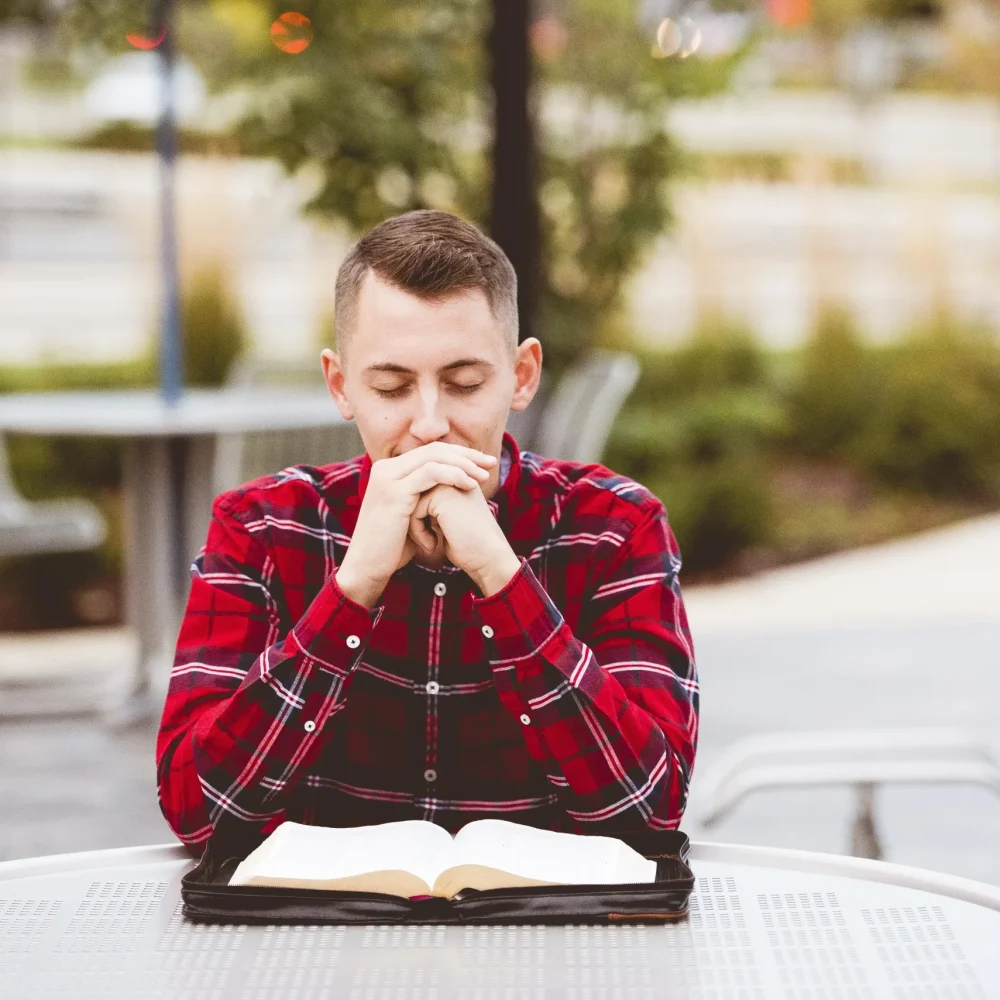 man-wearing-red-shirt-sitting-table-with-n-open-book-form-him (1)